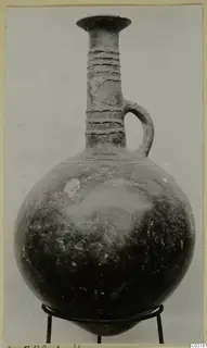 Red Polished III jug from Lapithos, a globular vessel with a tall neck and loop handle, on a metal stand