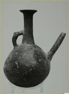 Round-bodied jug with a tall flared neck, a loop handle and a side spout, shown on a stand against a plain background.
