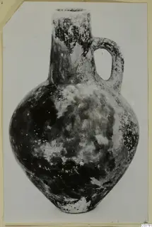 Red Polished III jug from Vomerus 81A, with a long neck, single loop handle and rounded body.