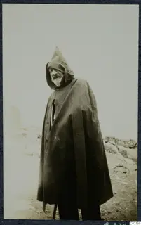 G. Jeffery standing at Vouni in a long dark cape with a pointed hood