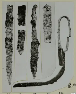 Iron objects from Marion Tomb 44, including long blade-like pieces and a loop-handled tool, shown on a mounted photograph