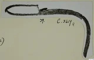 Metal tool with a loop at one end, shown on a pale card mounted on an album page