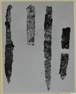 Five corroded iron knives and tool fragments from Marion, laid out on a plain grey ground.