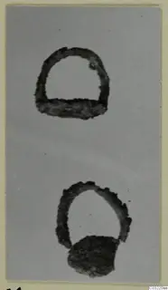 Two corroded iron objects on a plain grey background, one a semicircular loop with a flat base bar