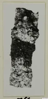 Fragment of an object from Marion, mottled dark and light, shown on a mounted card