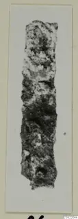 Long, narrow corroded fragment of an object from Marion, shown upright on a white card mount