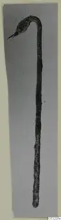 Bronze ladle with a long thin handle curving up to a small hooked bowl end