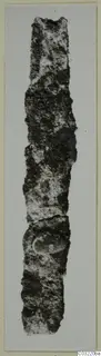 Corroded metal object from Marion, a long narrow fragment shown upright against a pale background