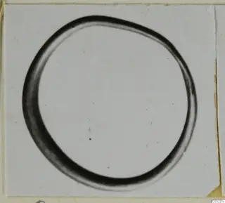 Closed ring with a thick, rounded section, photographed on a light card mount