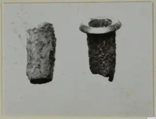 Two small corroded cylindrical objects side by side, one with a flared rim.