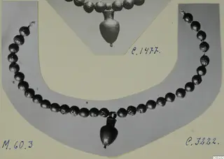 Necklace of round beads with a small vessel-shaped pendant, on a grey card mount beside a second necklace photo