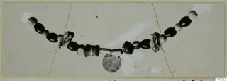 String of dark and pale beads with a disc-shaped pendant, from Marion