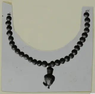 Necklace of small round dark beads with a pendant hanging from the centre