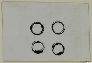 Four small rings photographed on a pale card, from Marion tombs 31-60