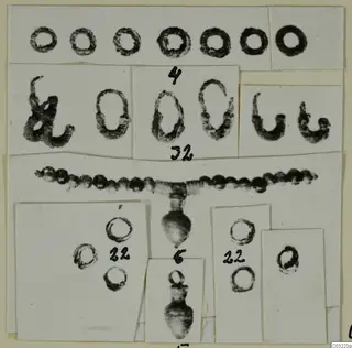 Mounted photographs of rings, a bead strand and pendants from Marion, with handwritten number labels.