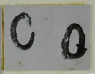 Two blurred, dark ring-shaped objects, one open and one closed, on a pale grey card.