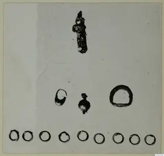 Small corroded rings, a pendant and an elongated metal object from Marion, laid out on a pale background