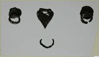 Four bronze mounting fragments on a pale card: two rounded loop pieces, a pointed plate and a small arc.