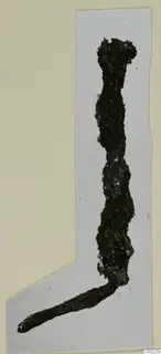 Corroded iron tool fragment, bent at an angle, shown on a grey card mount.