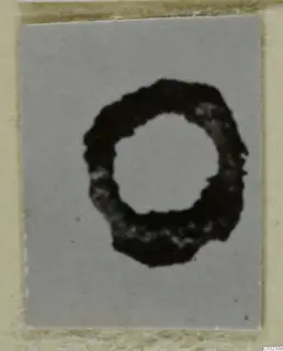 Corroded circular iron object from Marion finds, dark with a rough outer edge