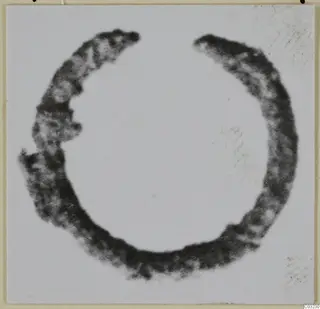 Open bronze ring with a dark, mottled surface, photographed against a pale background