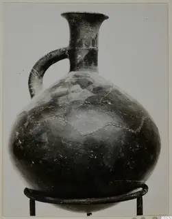 Red Polished III jug from Lapithos, with a single loop handle and flared neck, on a metal stand