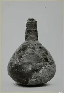 Black polished pottery vessel with a tall narrow neck, incised bands and concentric circles on the body