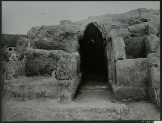 Excavated stone walls with a dark arched opening at the palace at Vouni
