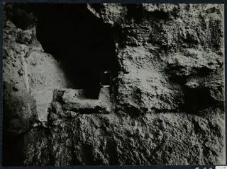 Rough stone face at Vouni palace with a dark recess and a stone ledge, seen during excavation