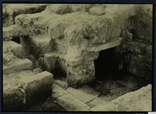 Excavated stone blocks and a flagged floor at the palace at Vouni, with a dark opening to the right