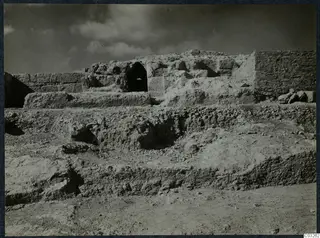 Excavated stone walls at Vouni palace, with a dark arched opening in the central wall