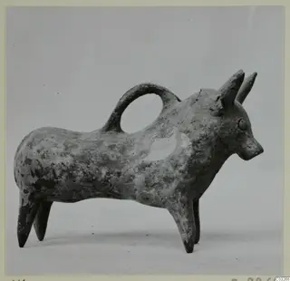 Bull-shaped pottery vessel with a loop handle over its back, in Base-Ring Ware, photographed against a grey backdrop