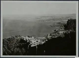 View from high ground over a bay at Vouni, with the sea on the left, a shoreline settlement and distant hills