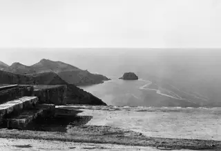 View across the sea from a stone terrace at Vouni towards a rocky islet off the coast