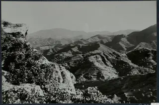 Landscape at Vouni with rolling hills, a rocky outcrop and shrubs in the foreground.