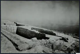 Ancient stone walls and a paved area on a height at Vouni, with hazy sea beyond.