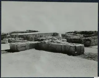 Excavated stone walls and blocks at the Vouni palace, with a large block structure behind them.
