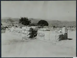 Ruined stone wall of large squared blocks at Vouni palace, with trees and hills behind