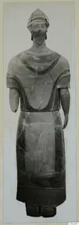 Terracotta statue of a standing bearded figure in a helmet-like cap, with short arms and painted bands on the body