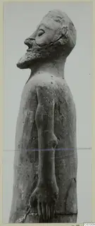 Terracotta statue of a standing bearded man with head tilted up, photographed from the side.