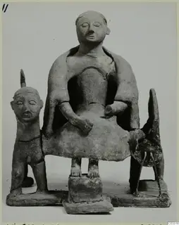 Terracotta group of a seated figure on a block-shaped seat, with a small standing figure and a four-legged animal beside it