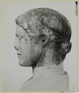 Marble head in left profile, hair with incised parallel lines, standing on a square plinth