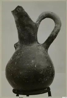 Red Polished III jug with a single loop handle and a broken spout, standing on a metal stand
