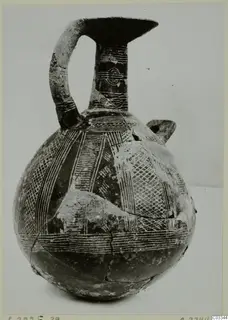 Pottery jug from Lapithos with a tall neck, strap handle and linear decoration on the body