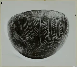 Red Polished III bowl with incised chevron and line decoration, photographed against a pale background