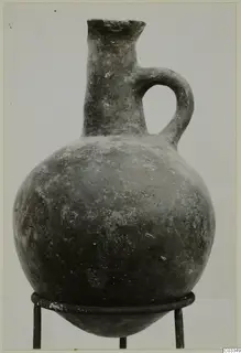 Pottery Red Polished II jug with a single loop handle, shown on a metal stand against a plain background.