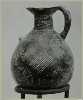 Pottery Red Polished II jug with incised concentric circles, zigzags and hatched bands, standing on a metal ring stand