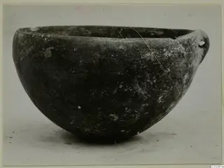 Pottery Red Polished III Bowl from Lapithos, shown in side view against a plain pale background