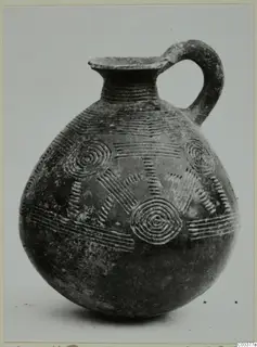 Pottery Red Polished II jug with a strap handle, incised with concentric circles and horizontal bands