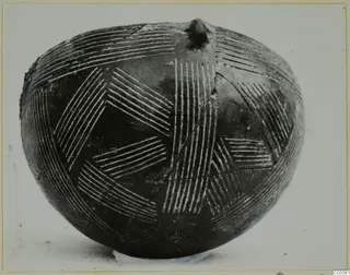 Dark polished vessel with a rounded body, incised hatched pattern filled with white, and a small knob on top
